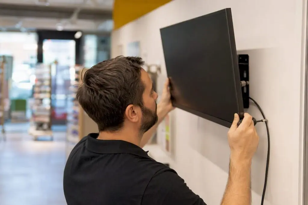 Technicien en train d’installer un écran dynamique en boutique